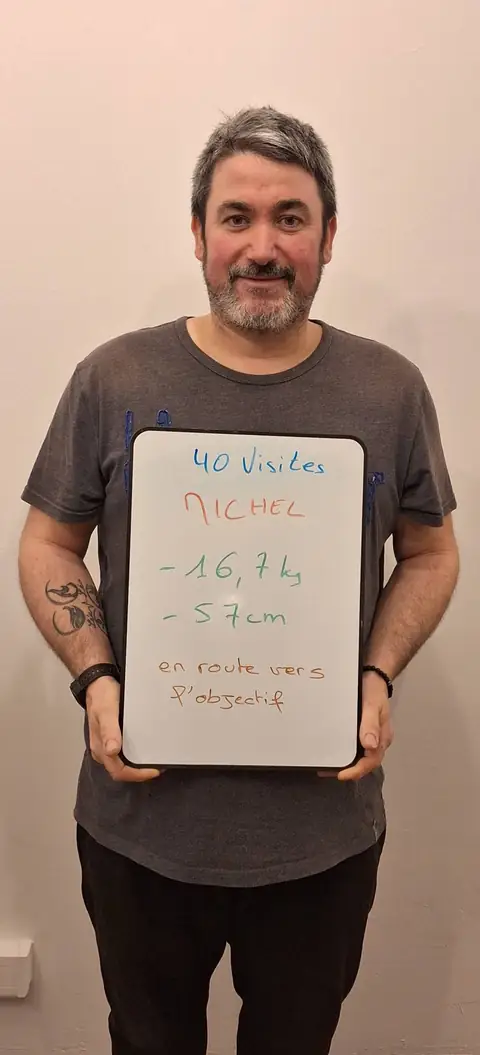 Un membre pose devant une ardoise blanche où sont notées ses mesures de bilan, au club