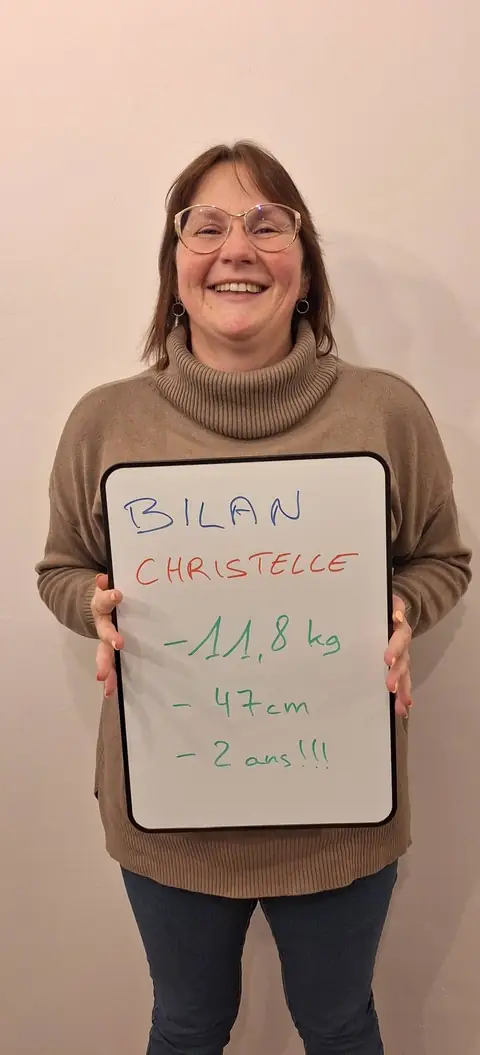 Une membre pose devant une ardoise blanche où sont notées ses mesures de bilan, au club